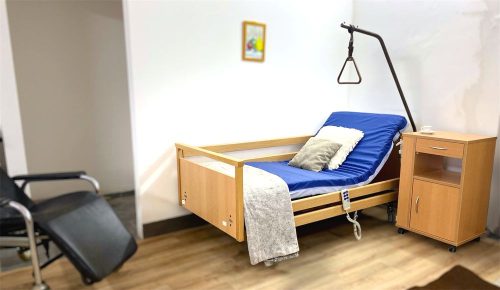 3 funkciós wissner-bosserhoff elektromos ápolási ágy, emelt háttámlával, kapaszkodóval és fa éjjeliszekrénnyel.