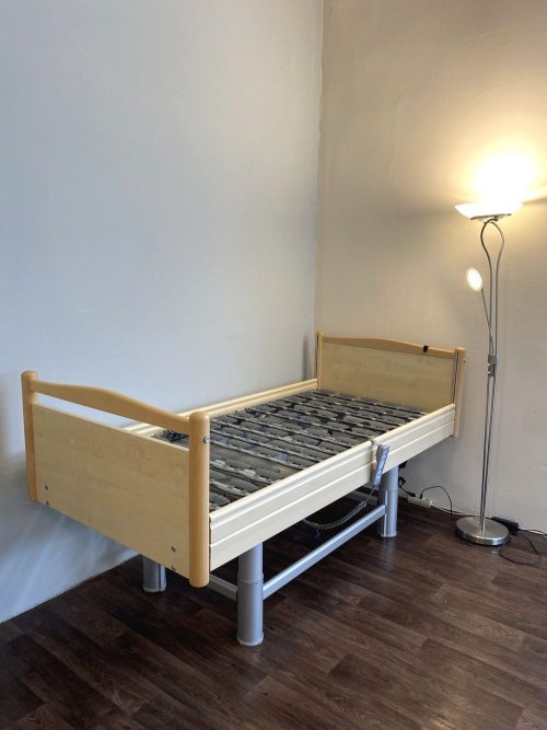 Elektromos betegágy maximális magasságra emelve, stabil fém szerkezettel és fa burkolattal.
