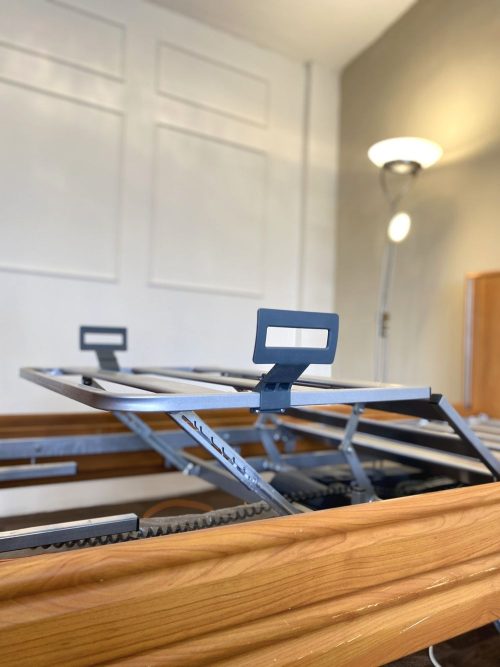 Emelt lábrésszel rendelkező fémrácsos ágykeret, matractartó fogantyúkkal.