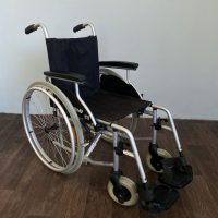 Összecsukható kézi kerekesszék masszív fémvázzal, fekete ülőfelülettel és ergonomikus karfákkal