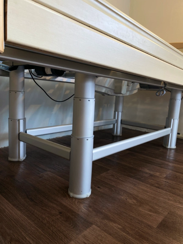 Elektromos ápolási ágy alsó váza és magasságállító lábak közelről.